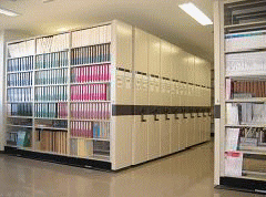 写真。図書館用の移動式書架と固定式書架があり、各書架に隙間なく医療専門の墨字図書と点字図書が収納されている。