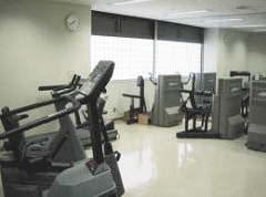 写真。トレーニング室内部。鏡張りの壁、ランニングマシーン、ローイングマシーン等のパワートレーニング機器を配置している。