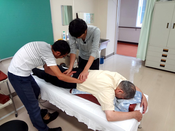 腰痛のアプローチを指導する芹澤氏（中央上）