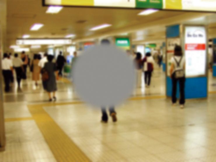 中心暗点 画像です。中心暗点の見え方を示しており、画像中央の駅の地下道を歩く男性の後ろ姿が灰色の円形で隠れています