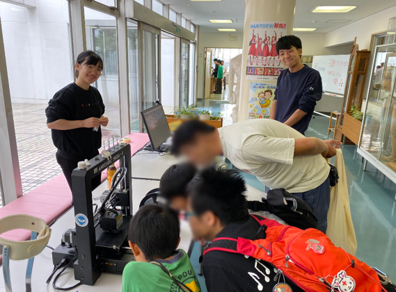 ３Dプリンターを覗き込む子供