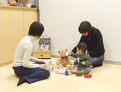 ぬいぐるみにケーキを食べさせる女の子の写真