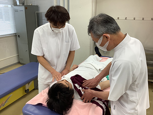 実技での指導の様子、利用者の施術に対して教員が手本を示しながら指導をしている
